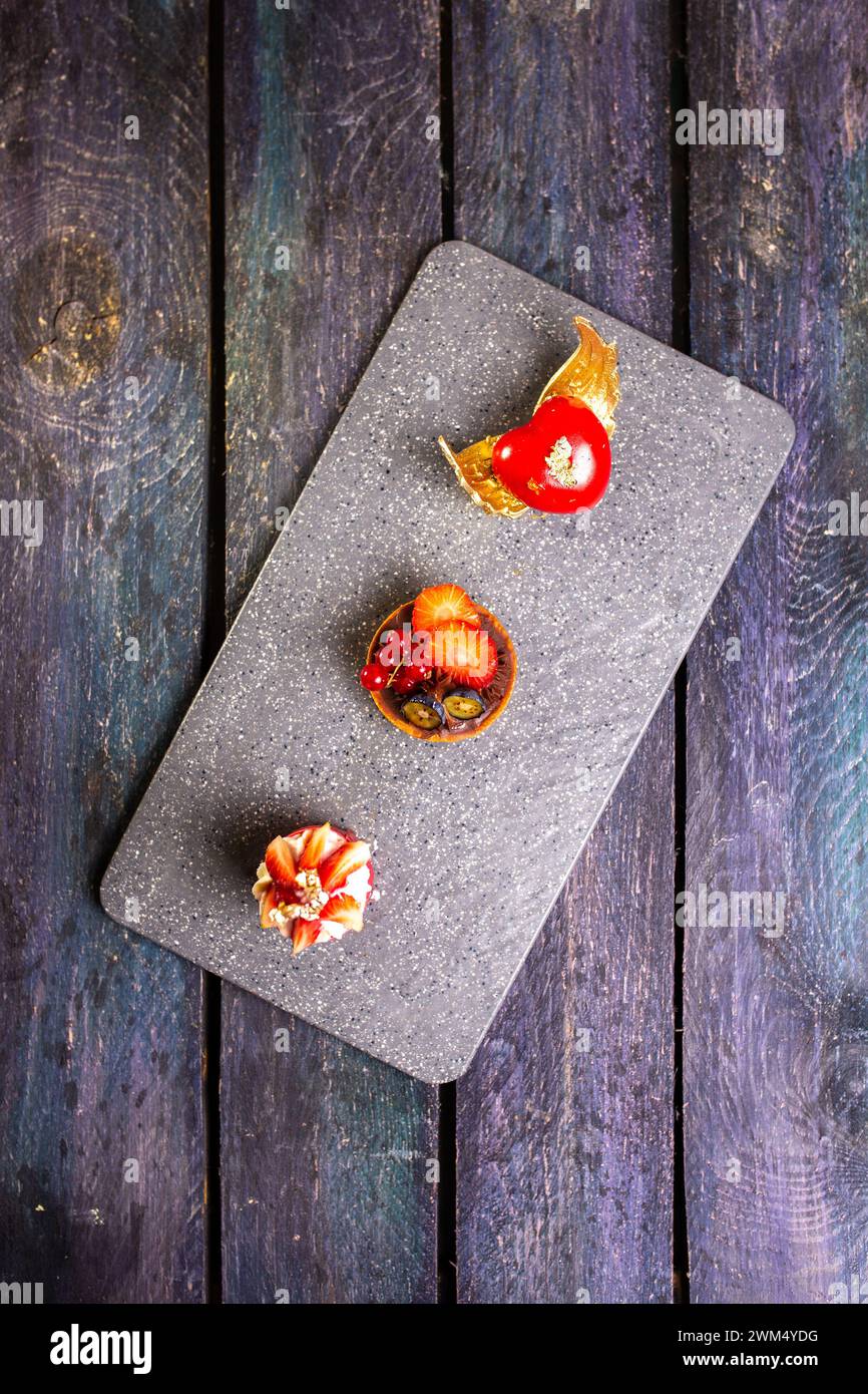 Eine exquisite Präsentation von vier dekadenten Kuchenscheiben, die elegant auf einem eleganten Marmorbrett angeordnet sind und ein Gefühl kulinarischer Opulenz wecken. Stockfoto