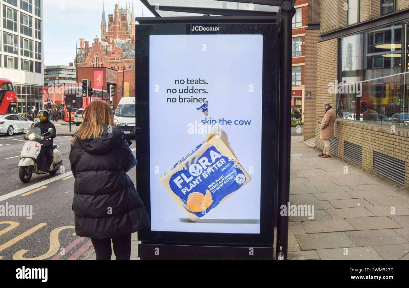 London, Großbritannien. Februar 2024. Eine Frau kommt an einer Werbung für Flora Pflanzenbutter in Zentral-London vorbei. Milchalternativen könnten gezwungen werden, ihre Namen zu ändern und die Verwendung von Variationen von Begriffen wie "Milch", "Butter" und "Käse" im Rahmen der vorgeschlagenen neuen Vorschriften, die behaupten, Verwechslungen zwischen pflanzlichen Erzeugnissen und Milcherzeugnissen zu vermeiden, einzustellen. Der Vorschlag wurde von pflanzlichen Lebensmittelherstellern kritisiert. Quelle: Vuk Valcic/Alamy Live News Stockfoto