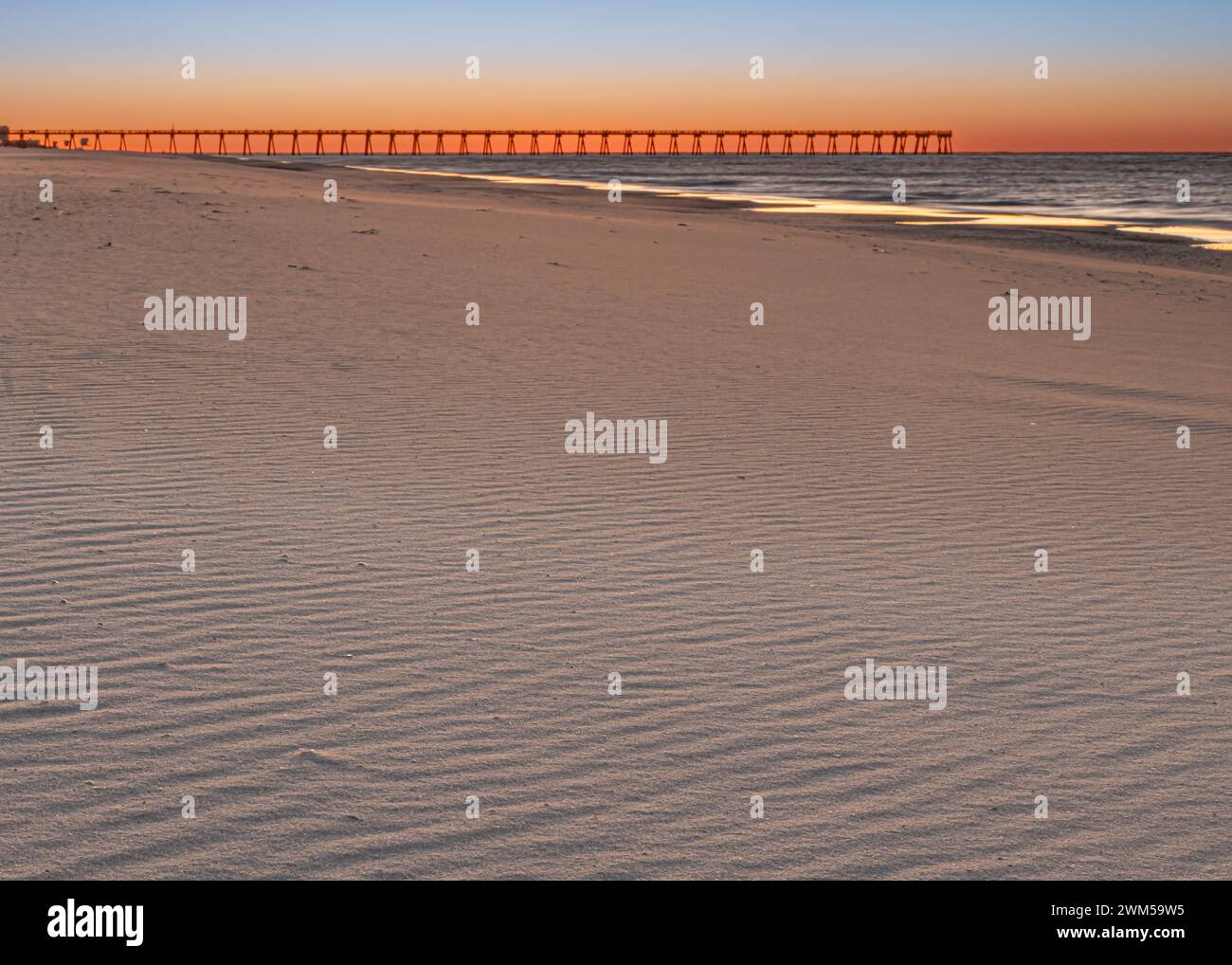 Der Sonnenaufgang erleuchtet den windgepeitschten Sand in der Nähe von Pensacola Beach Gulf Pier, Pensacola Beach, Golf von Mexiko, Florida. Stockfoto