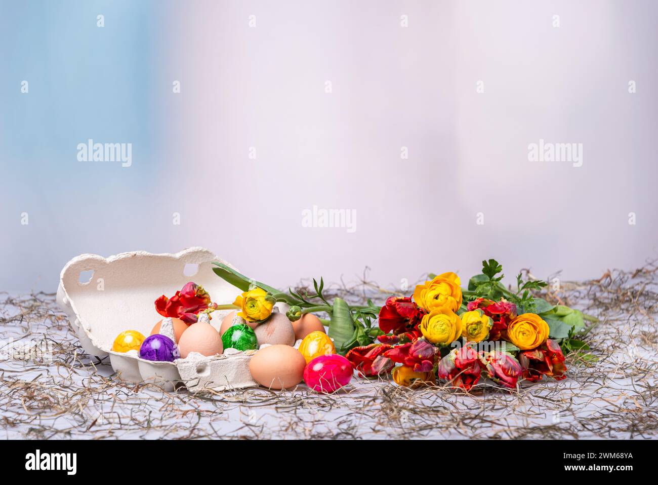 Bunte Ostereier auf einem Tisch mit Bumenstrauß als Postkartenmotiv zu Ostern Stockfoto