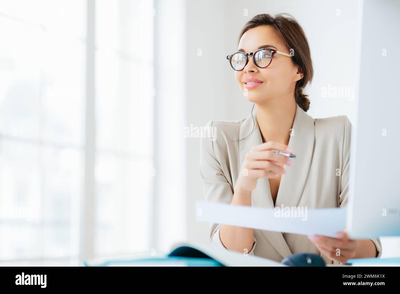 Aufstrebende Geschäftsfrau, die mit einem hoffnungsvollen Blick einen Bericht liest. Stockfoto