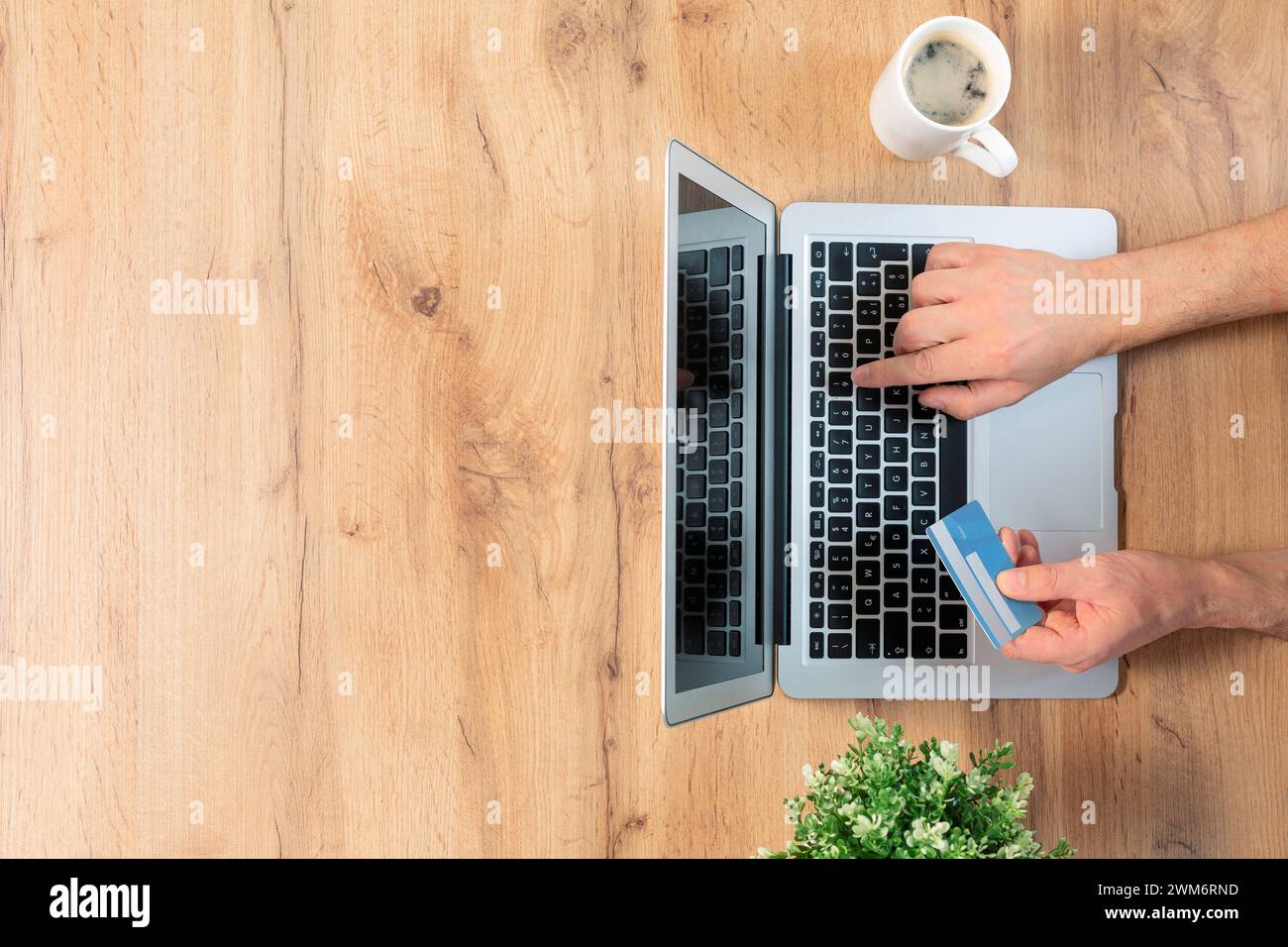 Draufsicht auf männliche Hände, die eine Online-Zahlung tätigen - Laptop auf Holzhintergrund mit Copyspace Stockfoto