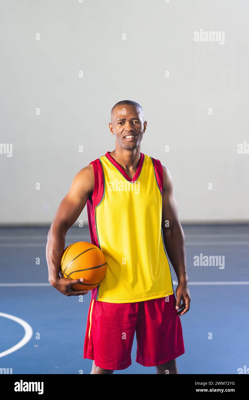 Ein afroamerikanischer Mann posiert selbstbewusst auf einem Basketballfeld Stockfoto