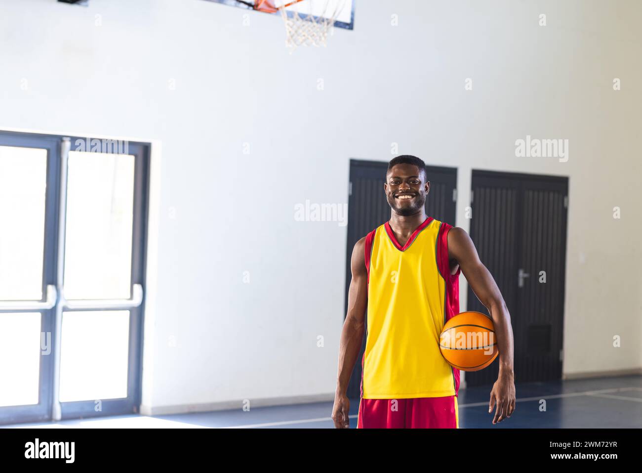 Ein junger Afroamerikaner steht stolz auf einem Basketballfeld Stockfoto