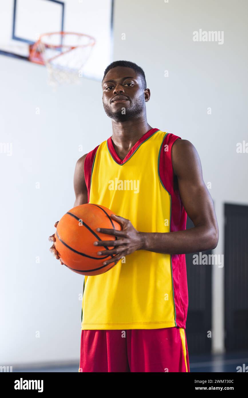 Ein selbstbewusster Afroamerikaner hält Basketball in einem Fitnessstudio Stockfoto