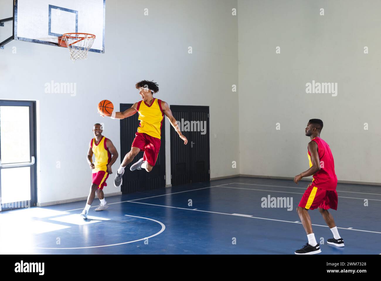 Junger afroamerikanischer Mann springt für einen Basketballschuss in einem Fitnessstudio Stockfoto