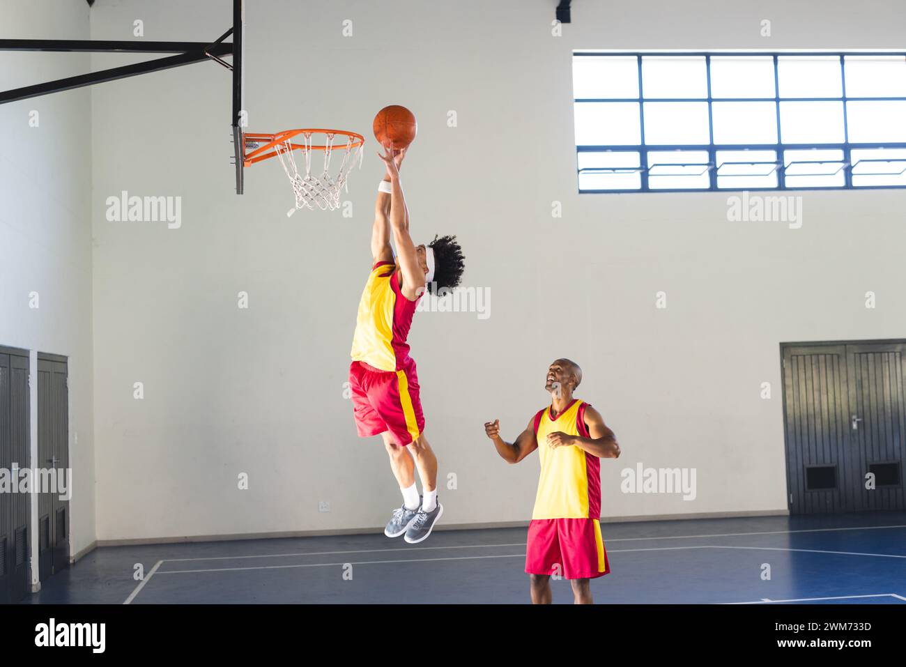 Afroamerikaner trainiert junge Männer im Basketball Stockfoto
