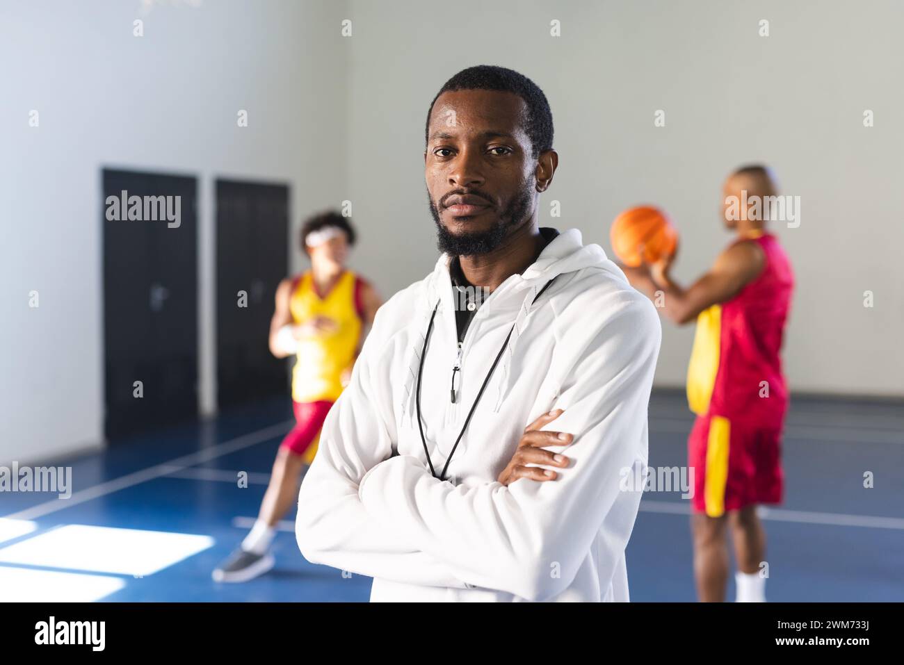 Der afroamerikanische Trainer steht selbstbewusst in einem Fitnessstudio, die Arme überkreuzt Stockfoto