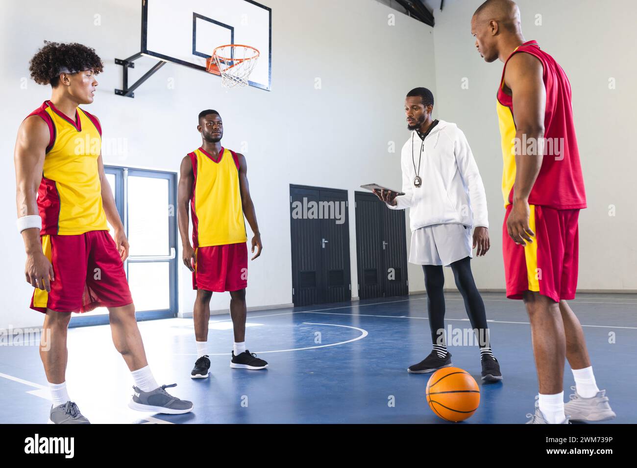 Afroamerikanischer Trainer diskutiert Strategie mit Basketballspielern in einem Fitnessstudio mit Kopierraum Stockfoto