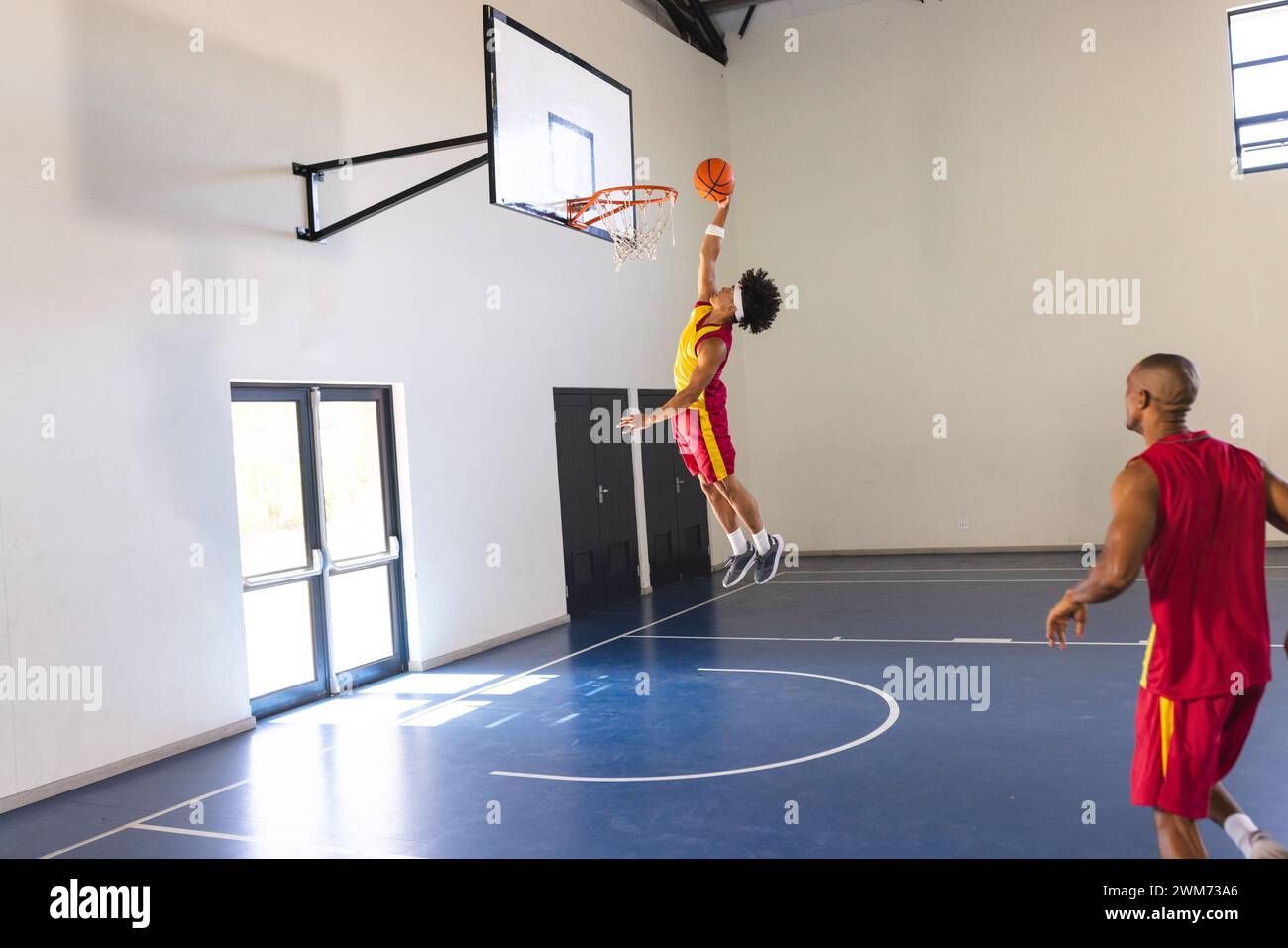 Afroamerikaner taucht Basketball auf einem Hallenplatz ein Stockfoto