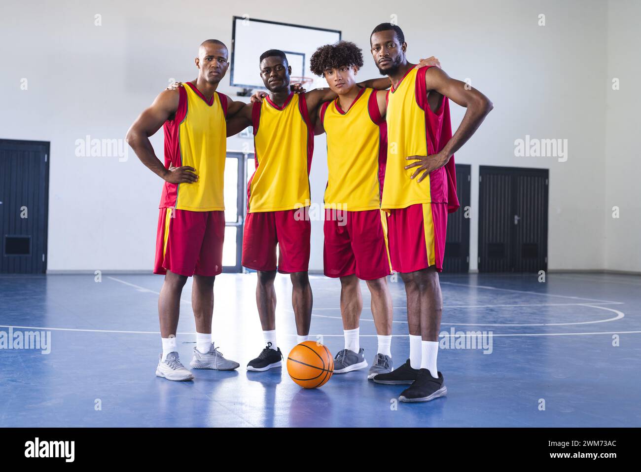 Ein vielseitiges Basketballteam posiert selbstbewusst auf dem Platz Stockfoto