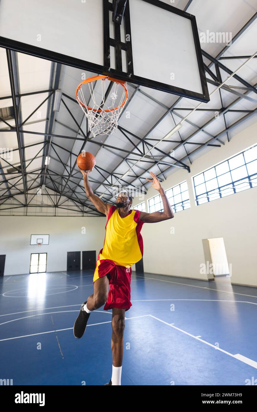 Ein Afroamerikaner punktet während eines Basketballspiels in einem Hallenplatz mit Kopierraum Stockfoto