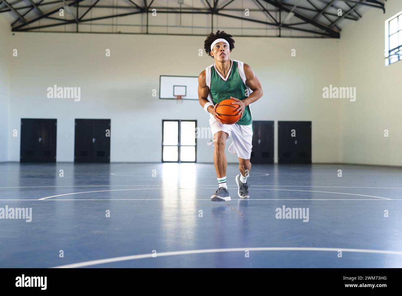 Junger birassischer Mann spielt Basketball drinnen, mit Kopierraum Stockfoto