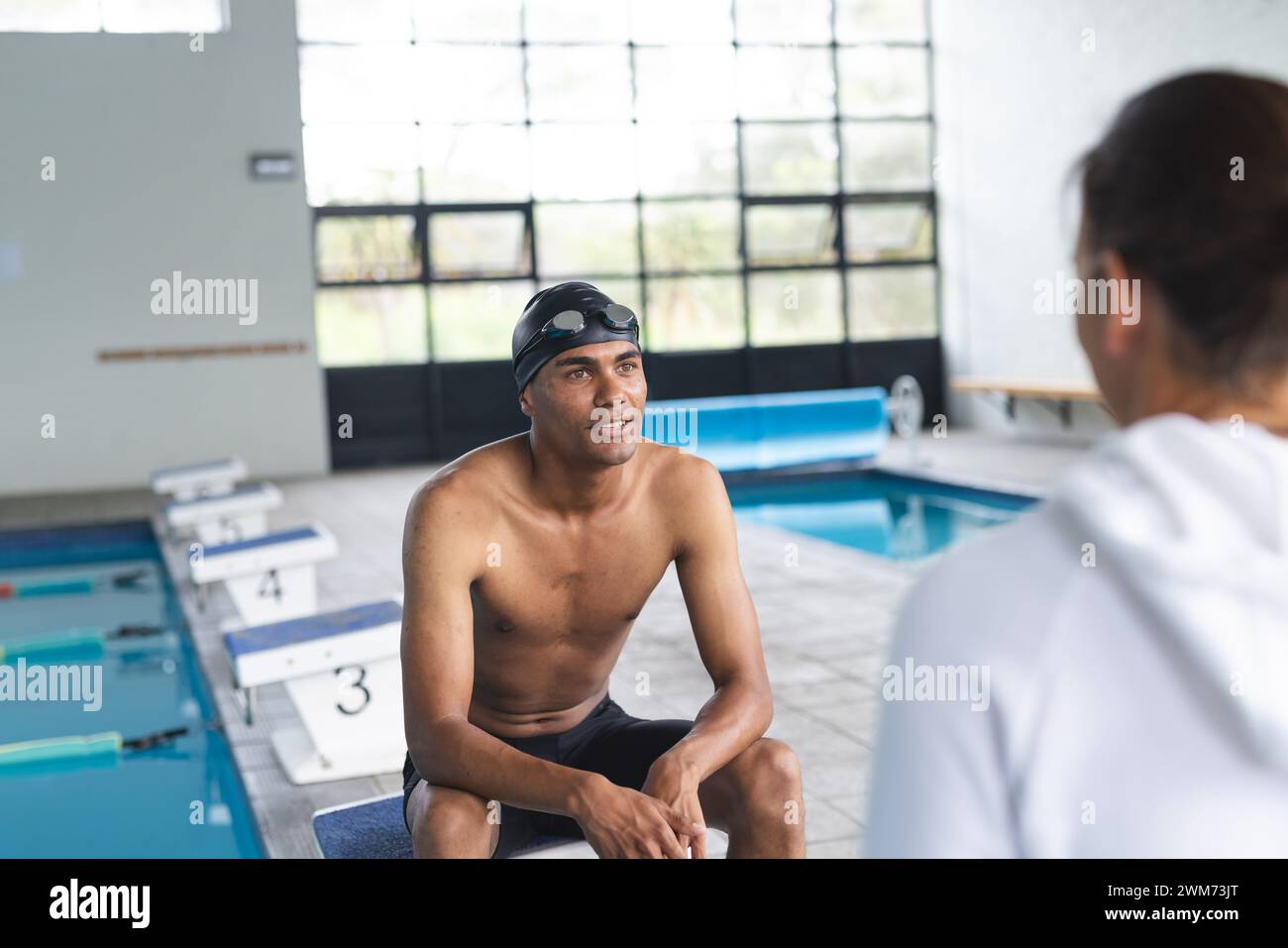 Ein junger männlicher Sportler sitzt am Pool und führt Gespräche Stockfoto