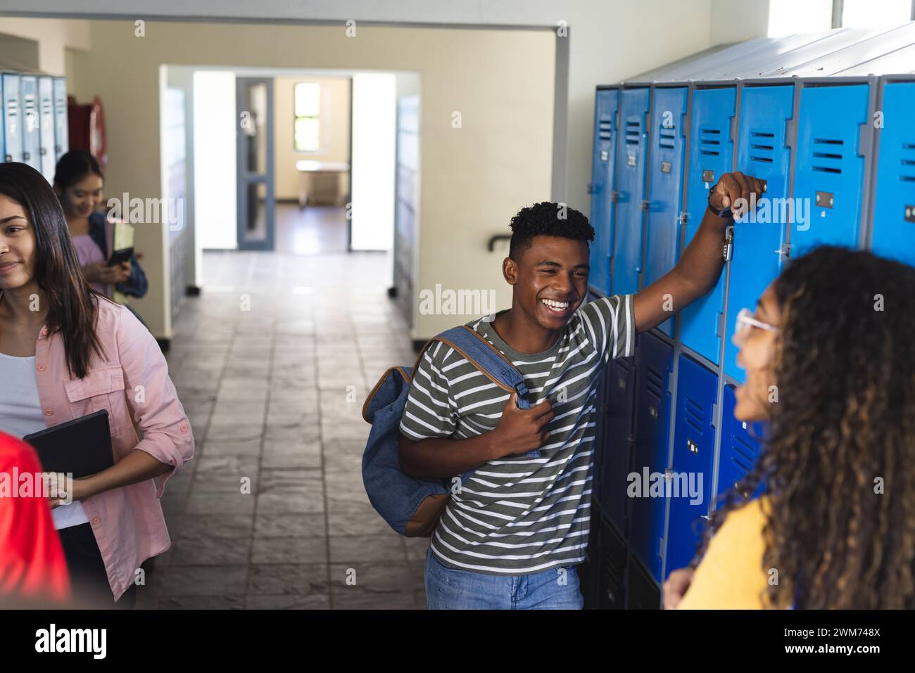 Teenager-Biracial-Junge, der in High School-Schließfächern plaudert Stockfoto