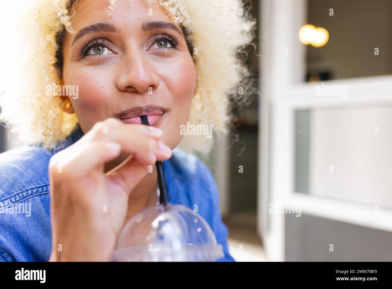 Die junge Frau genießt ein kaltes Getränk drinnen mit Kopierraum Stockfoto