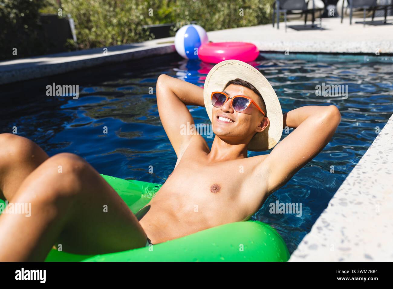 Ein asiatischer junger Mann entspannt sich auf einem Schwimmbecken Stockfoto