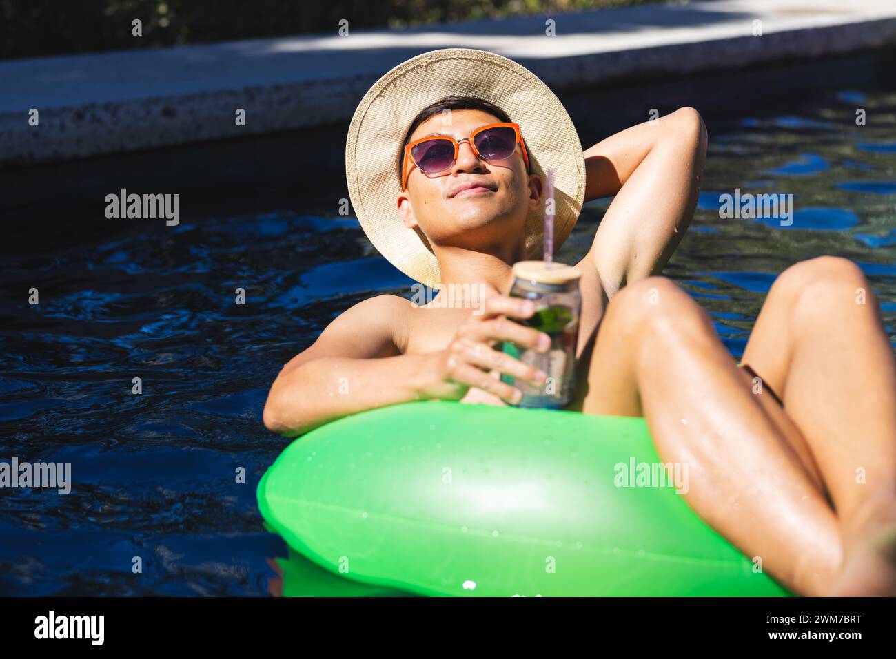 Junger asiatischer Mann entspannt sich auf einem Schwimmbecken Stockfoto