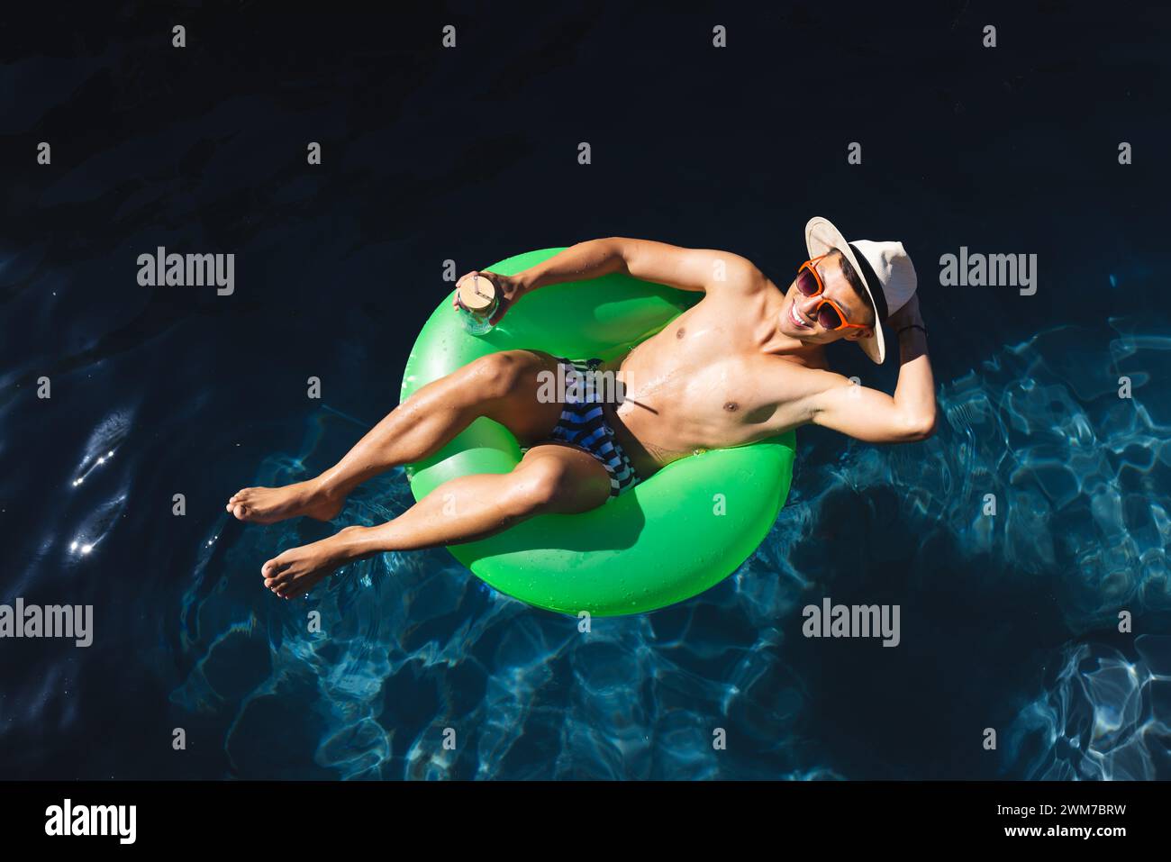Junger asiatischer Mann entspannt sich auf einem Schwimmbecken Stockfoto