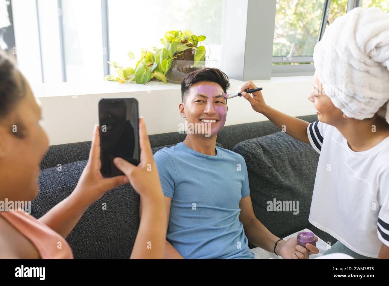 Ein junger asiatischer Mann wird von einer jungen Frau zu Hause geschminkt Stockfoto