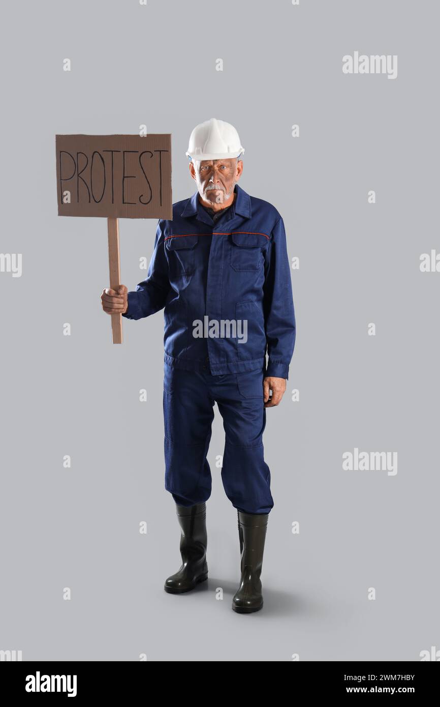 Protestierender Bergmann mit Plakat auf grauem Hintergrund Stockfoto