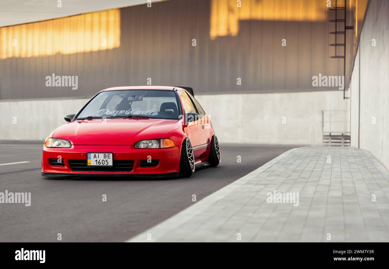 Sehr niedriger roter Honda Fließheck in einem Hof. Beispiel für eine Auto-Tuning-Kultur – geparkte Civic EG in der Nähe der Bordsteinkante. Selektives Fokusbild. Stockfoto