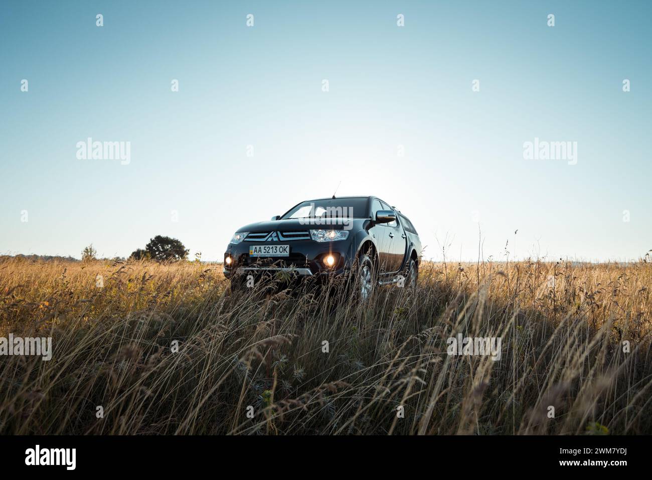 Schwarzer Mitsubishi SUV-Pickup-Truck auf einer Wiese. Morgenlicht um 6:00 Uhr, Dreiviertelblick. Stockfoto