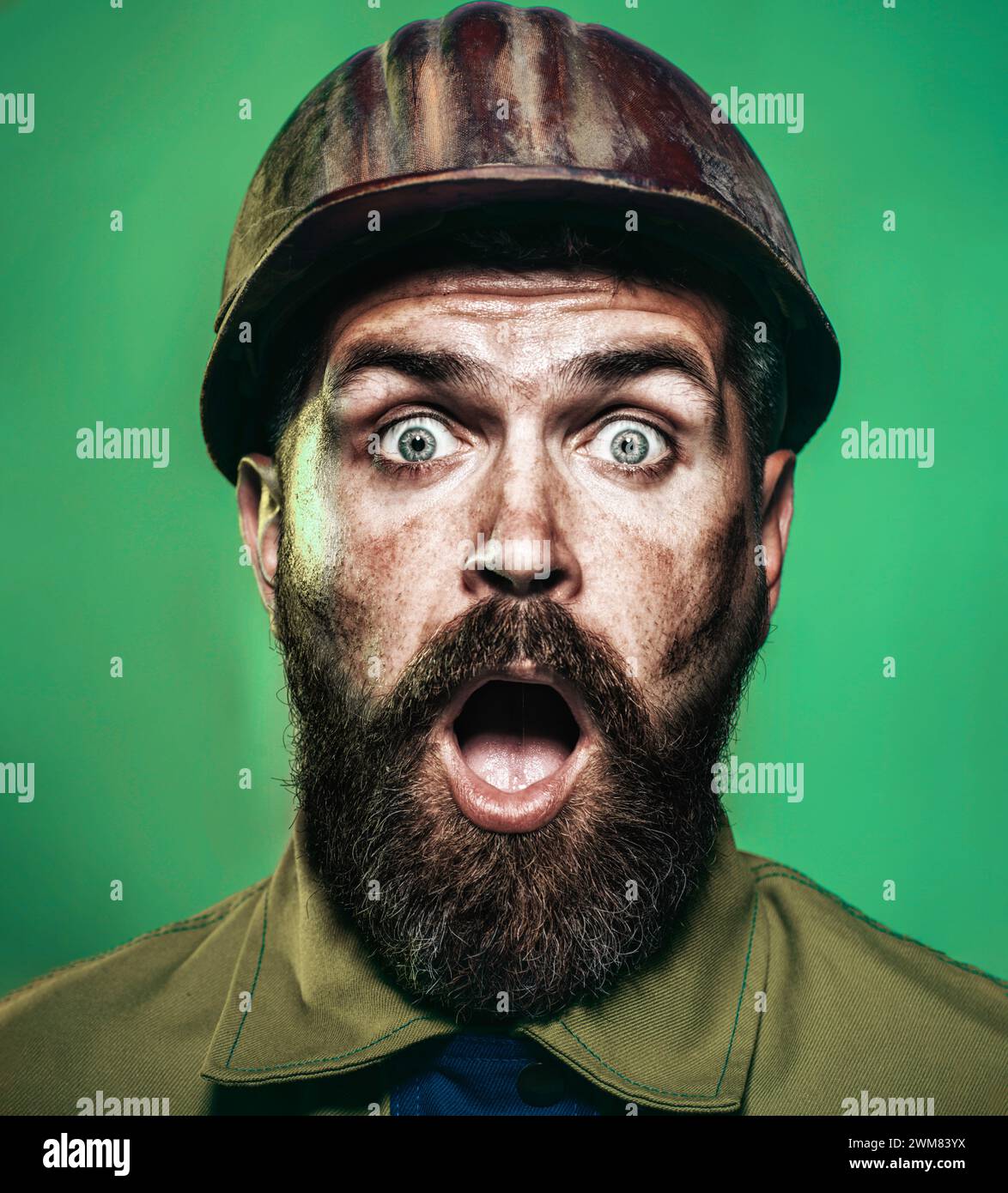 Nahaufnahme des Bauarbeiters im Schutzhelm. Verblüffter bärtiger Baumeister im Schutzhelm. Professioneller Vorarbeiter, Handwerker an Stockfoto