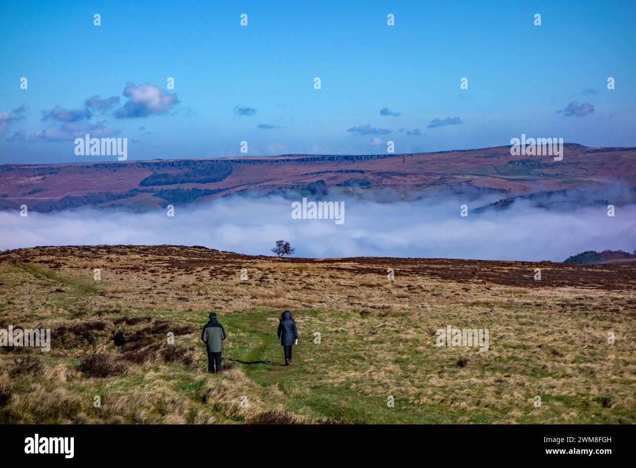 Menschen, die über das Eyam Moor im englischen Derbyshire Peak District spazieren, mit einem Nebel im Tal Stockfoto