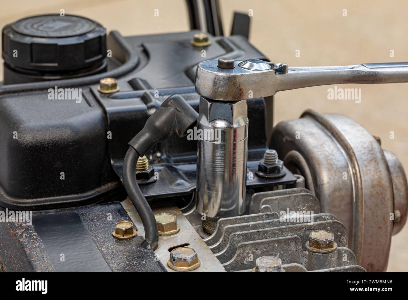 Entfernen der Zündkerze vom Motor des Rasenmähers mit Steckschlüssel. Reparatur, Wartung und Service von Rasen- und Gartengeräten. Stockfoto