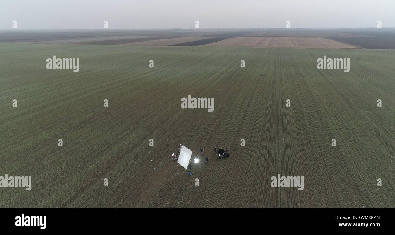 Filmcrew, die eine Szene im Schnittfeld aufbaut. Trübe Winter-Drohnenaufnahme. Stockfoto