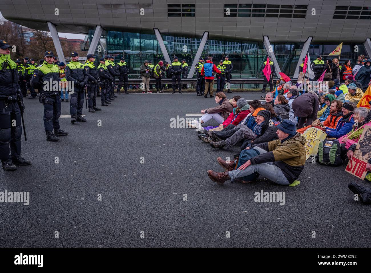 Amsterdam, Nordholland, Niederlande. Februar 2024. Die niederländische Polizei umgibt eine Gruppe von Aktivisten, die die Autobahn A10 blockieren. Aktivisten blockierten die A10, eine Hauptstraße in Amsterdam, Niederlande. Ihre Forderung lautete, dass die ING Bank ihre Investitionen in die fossile Brennstoffindustrie einstellen sollte. (Kreditbild: © James Petermeier/ZUMA Press Wire) NUR REDAKTIONELLE VERWENDUNG! Nicht für kommerzielle ZWECKE! Stockfoto