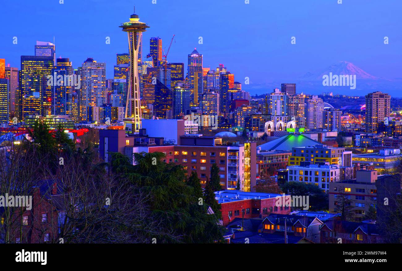 Hervorragender Blick auf die Innenstadt von Seattle vom Queen Anne Hill in der Abenddämmerung mit den Lichtern der Stadt, die mit der Space Needle leuchten, und Mt. Rainier im Hintergrund Stockfoto