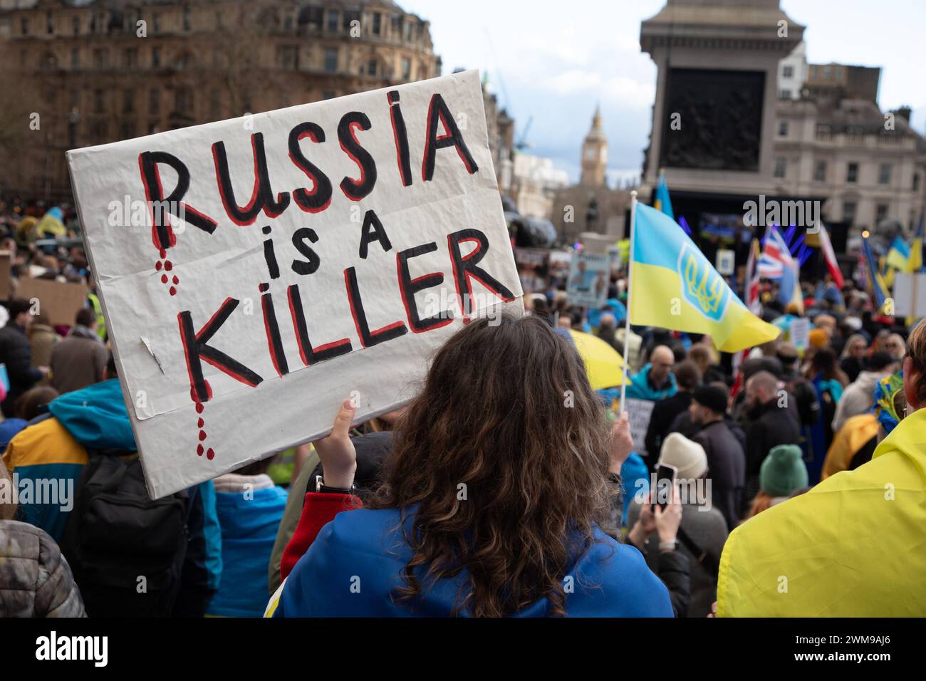 London, Großbritannien. Februar 2024. Ein Demonstrant hält ein Schild auf dem Trafalgar-Platz, auf dem sich Tausende versammelt haben, um am zweiten Jahrestag der russischen Invasion solidarisch mit der Ukraine zu stehen. Quelle: Kiki Streitberger/Alamy Live News Stockfoto