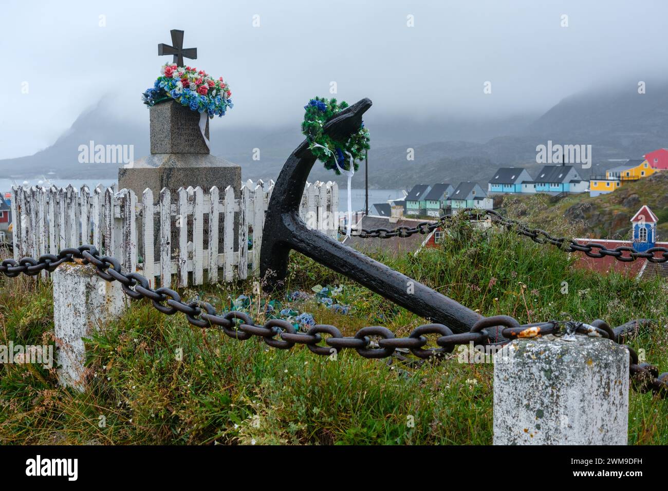 Ein Denkmal und ein großer Schiffsanker sind mit Blumenkränzen geschmückt. Sisimiut, Grönland. Stockfoto