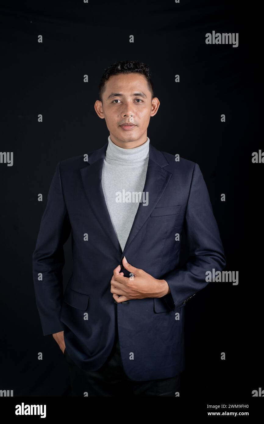 Porträt eines schönen eleganten Mannes in schwarzem Anzug auf schwarzem Hintergrund. Studio-Modus Hochformat Stockfoto