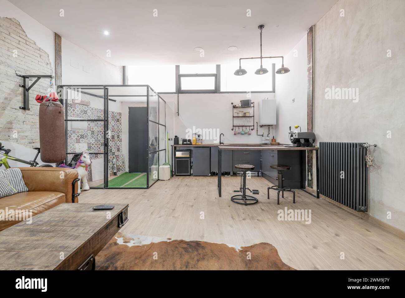 Großes offenes Wohnzimmer einer Loftwohnung mit industrieller Dekoration mit Metallblasenstrukturen mit transparenten Paneelen im Flur Stockfoto