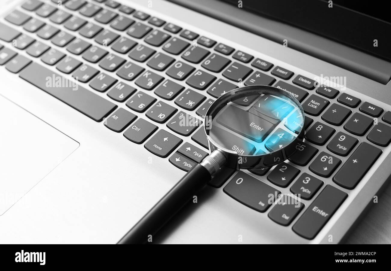Eine Lupe auf einer Laptop-Tastatur mit einer blauen Reflexion im Glas. Konzept der Informationssuche Stockfoto