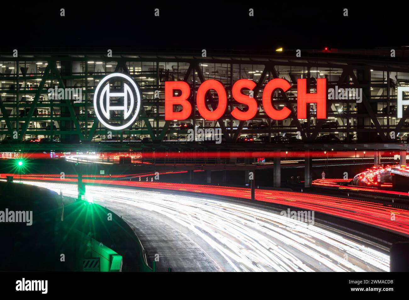 Autobahn A8 am Flughafen Stuttgart mit Bosch-Parkhaus am Abend bilden Autos leichte Wege. Die 440 Meter lange Konstruktion bietet Stockfoto