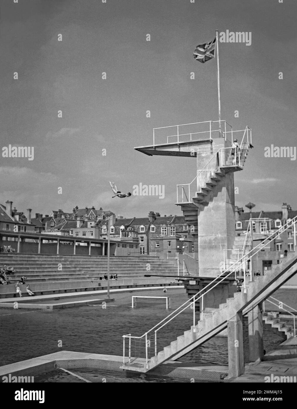 Ein Mann taucht von den Brettern im Hastings St. Leonards Bade Pool, Seaside Road, St. Leonards-on-Sea, East Sussex, England, UK c.1950. Der beeindruckende lido wurde 1933 eröffnet. Das Schwimmbad wurde von Sidney Little entworfen und gebaut, dem Borough Engineer. Der riesige Pool war 15 Meter tief unter der Betontauchplattform. Im Pool gab es viele Schwimm- und Tauchveranstaltungen sowie Mode- und Schönheitsshows. Da Pauschalreisen im Ausland immer beliebter wurden, gingen die Badezahlen zurück und der Pool wurde 1959 geschlossen. Es wurde ein Ferienlager (1960–86). Sie wurde 1993 abgerissen. Stockfoto