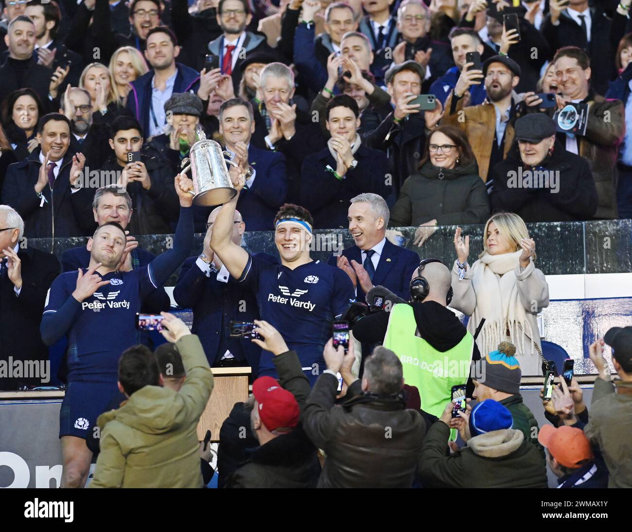 Scottish Gas Murrayfield Stadium. Edinburgh, Großbritannien. Februar 2024. UK. Die Herren Guinness Six Nations spielen Schottland gegen England die schottischen Co-Captains Finn Russell (L) und Rory Darge (R) heben den Calcutta Cup auf und sehen den schottischen Hollywood-Star Gerard Butler (oben rechts weißes T-Shirt) feiert den Sieg im Rugby-Spiel Schottland-England, während er eine Pause von den Dreharbeiten in Nordirland einlegt. Quelle: eric mccowat/Alamy Live News Stockfoto