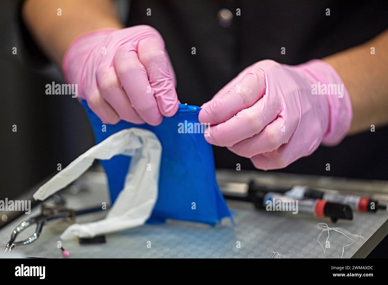 Zahnarzt zieht vor der Behandlung und Restauration des Zahnes eine Gummizahnmutter an. Zahnpflege und -Pflege Stockfoto