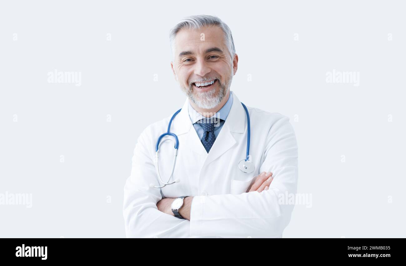 Selbstbewusster Arzt posiert mit überkreuzten Armen und lächelnd, Gesundheitswesen und Medizin Konzept Stockfoto
