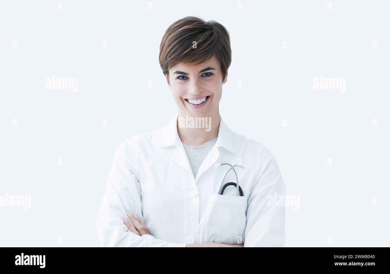 Selbstbewusste Ärztin posiert mit gekreuzten Armen und lächelt in die Kamera, Gesundheitskonzept Stockfoto