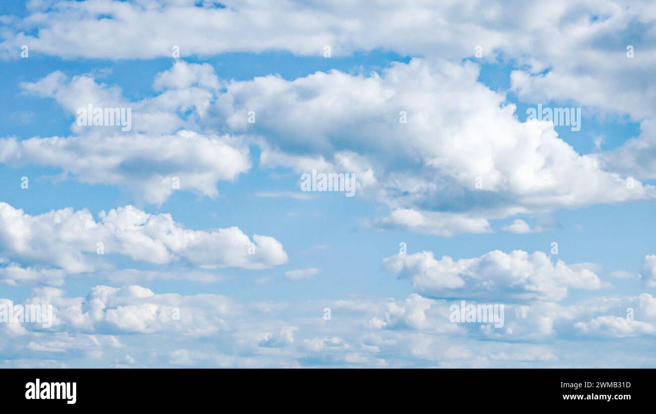 Flauschige weiße Wolken verstreut in der blauen Weite. Stockfoto