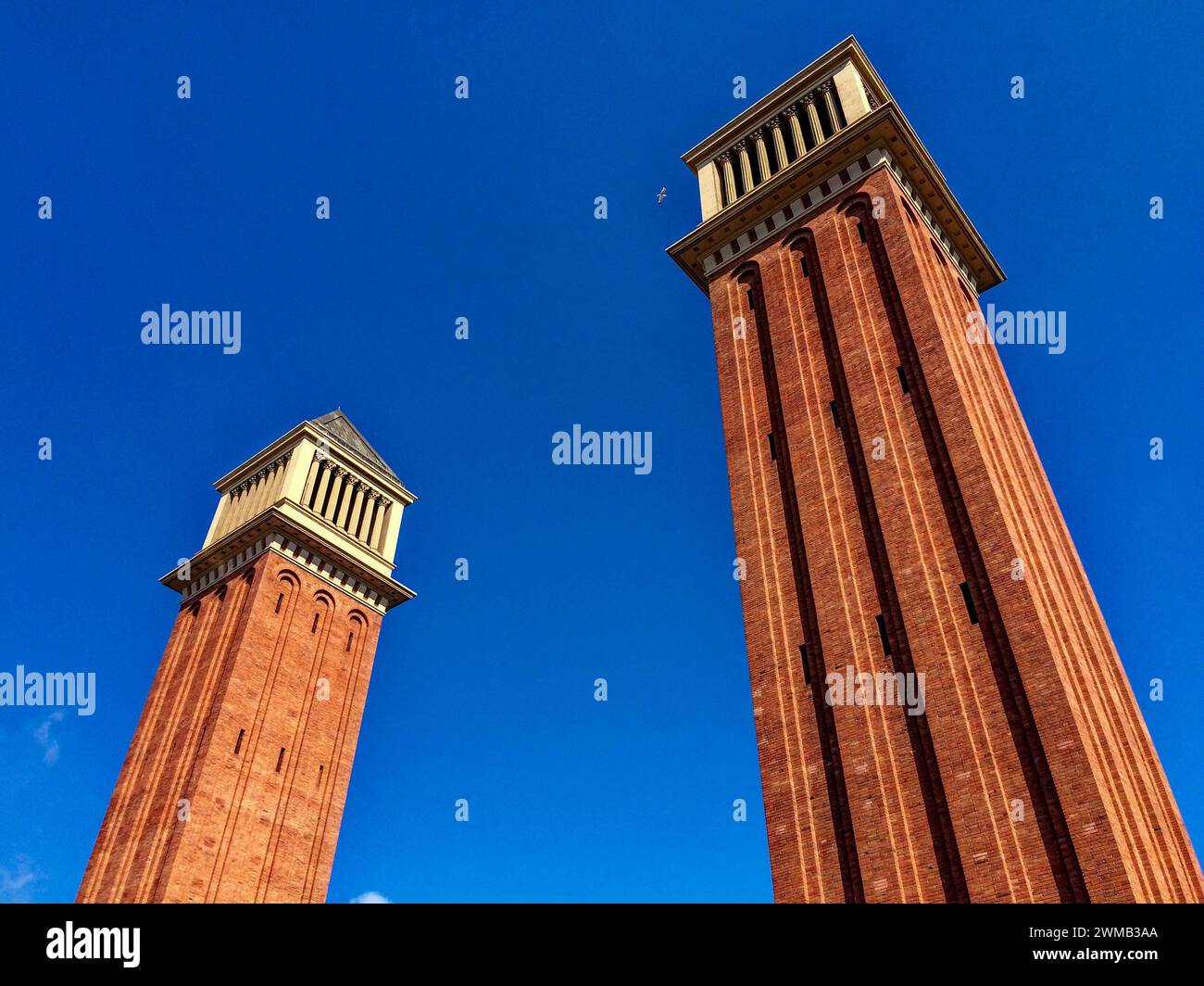 Das Bild zeigt zwei hohe rote Backsteintürme mit weißen architektonischen Details unter einem klaren blauen Himmel. Stockfoto