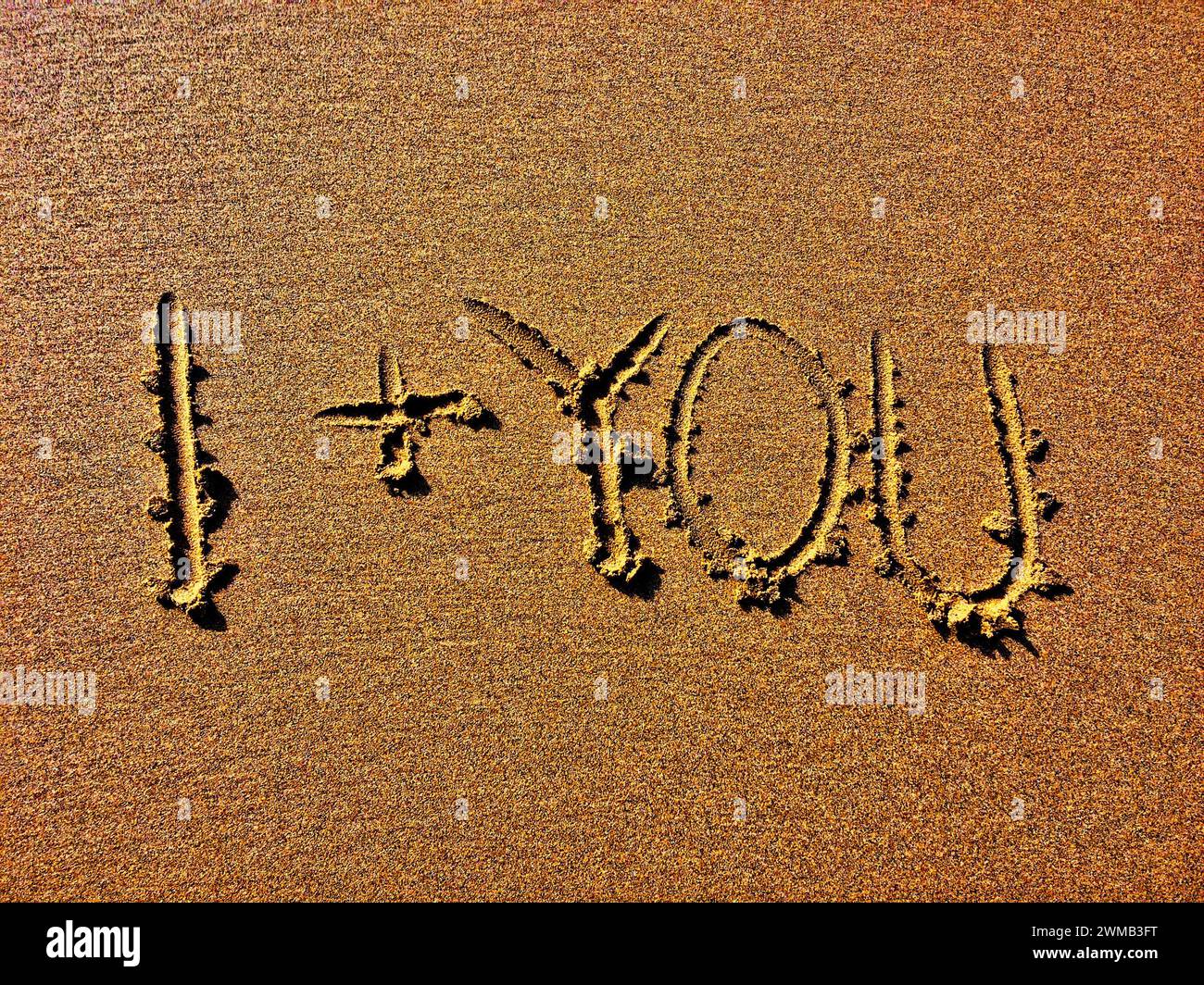 Das Bild zeigt „I + YOU“ tief in eine sandige Oberfläche eingeätzt. Stockfoto