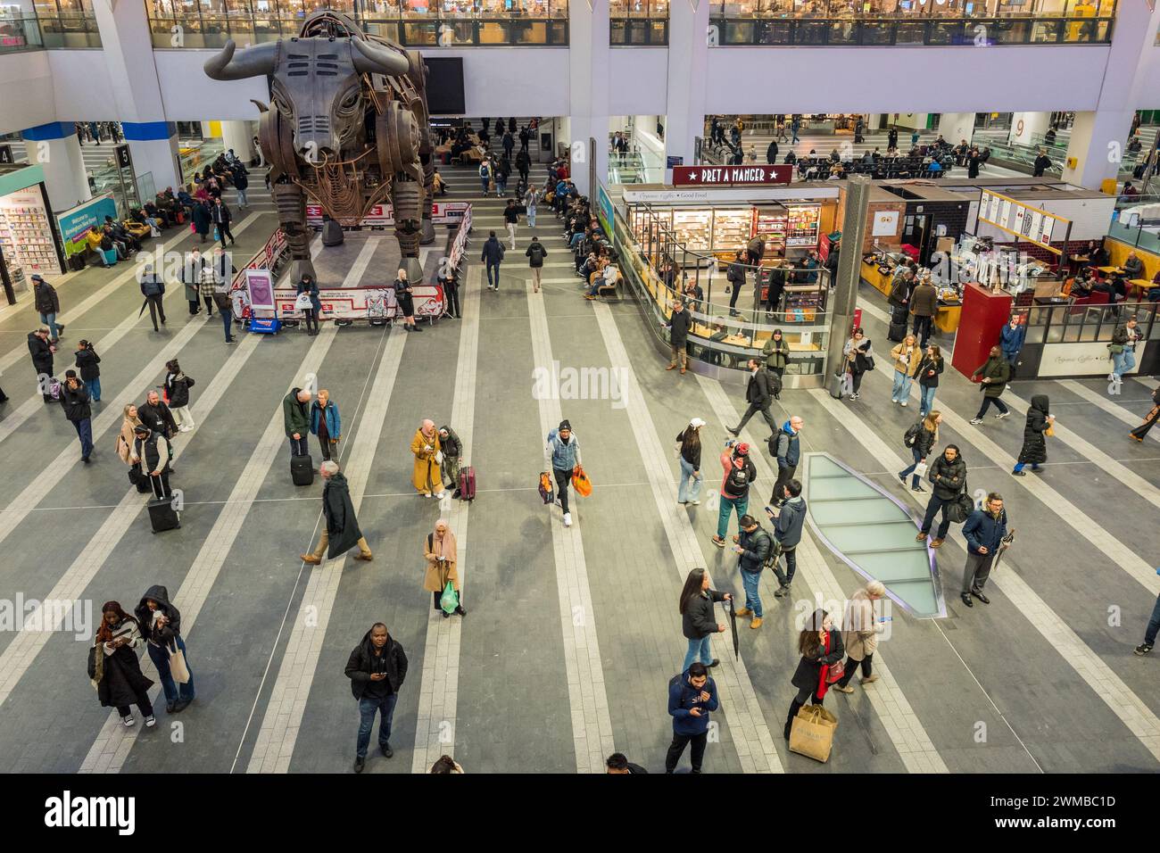 Kunden und Passagiere am Bahnhof Birmingham New Street, gehen und stehen im Hauptfoyer mit Ozzy, dem tobenden Bullen. Stockfoto