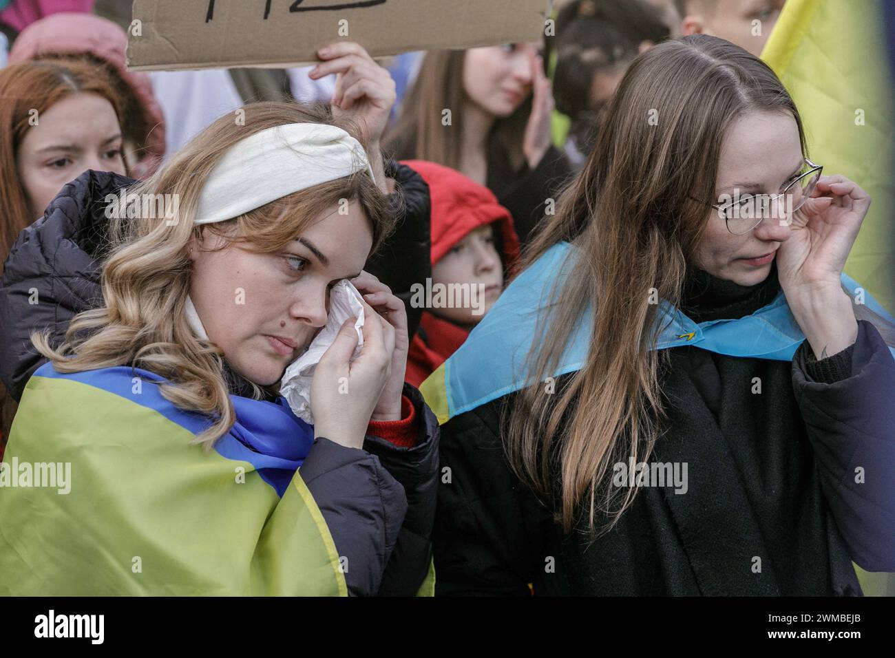 Mädchen wischen Tränen weg, während sie ein ukrainisches Lied bei der Kundgebung zum zweiten Jahrestag der Invasion Russlands in die Ukraine in der Nähe der Botschaft der Russischen Föderation in Warschau aufführen. Polen ist ein Land, das in den ersten Tagen der massiven Invasion Russlands in die Ukraine am 24. Februar 2022 die größte Zahl von Flüchtlingen aus der Ukraine aufgenommen hat. Am zweiten Jahrestag der Invasion nahmen mehrere Tausend Menschen an der Kundgebung in der Nähe der Botschaft der Russischen Föderation in Warschau Teil. Stockfoto