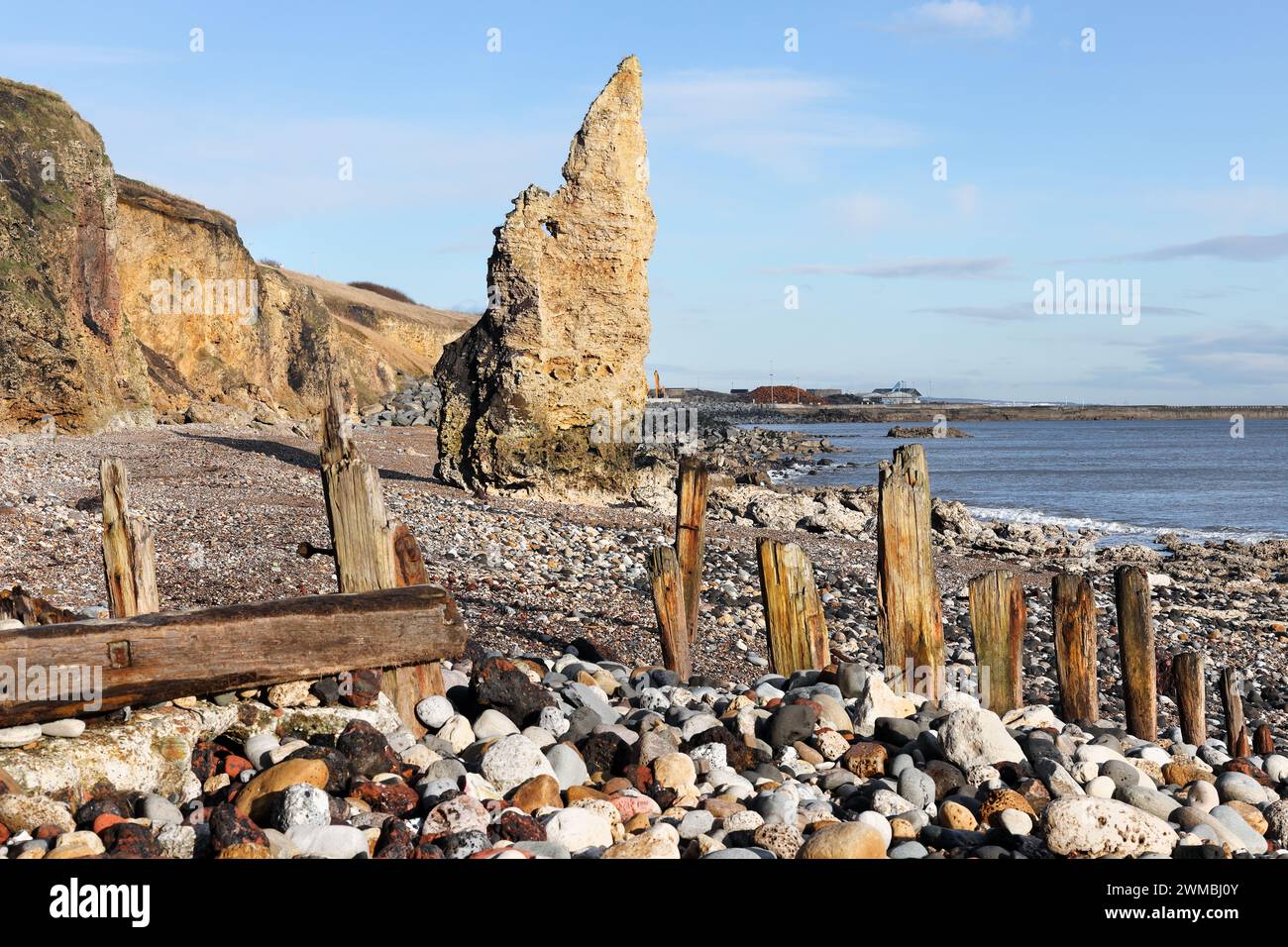 Magnesian Kalkstein Seestapel und wetterabgenutzt Timber Groynes am Seaham Chemical Beach, Durham Heritage Coast, Seaham, County Durham, Großbritannien Stockfoto